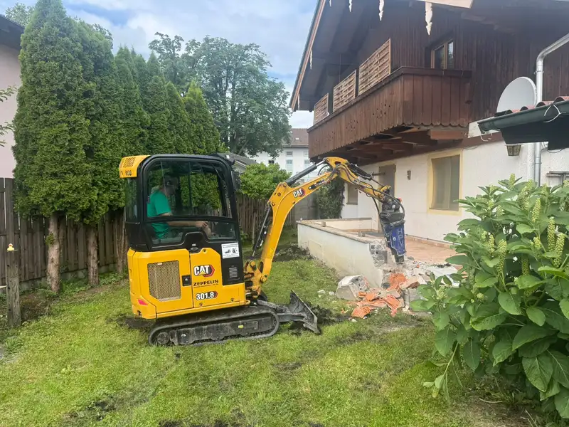 Minibagger beim Abbruch einer Mauer am Haus