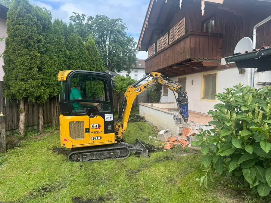 Minibagger reißt die alte Betonmauer am Haus ab