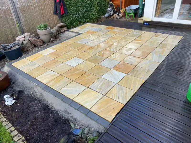 Terrasse aus Sandsteinplatten neben einer Holzterrasse