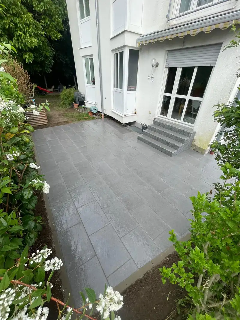 Terrasse aus großformatigen Platten mit Stufen zum Hauseingang