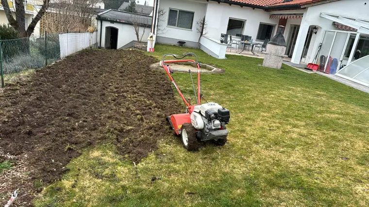 Rote Motorhacke auf umgegrabenem Rasen im Garten