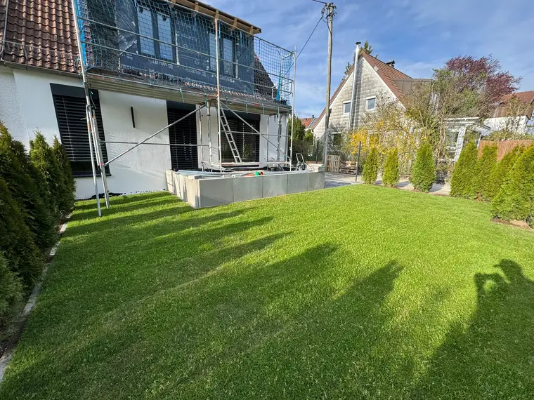Einfamilienhaus mit Gerüst und grünem Rasen im Garten