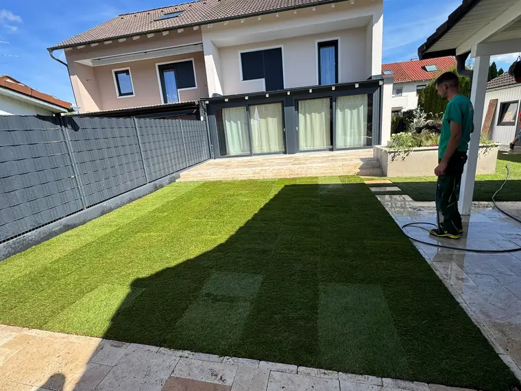 Mann bewässert frisch verlegten Rollrasen im Garten