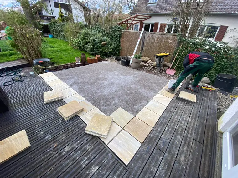 Arbeiter beim Verlegen von Terrassenplatten im Garten
