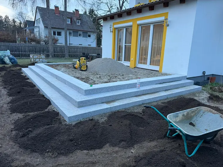Baustelle einer Terrasse mit Granitstufen, Kies und Schubkarre