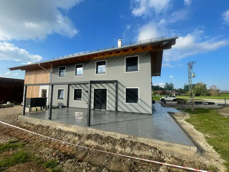 Modernes Einfamilienhaus mit grau gepflasterter Terrasse und Überdachung