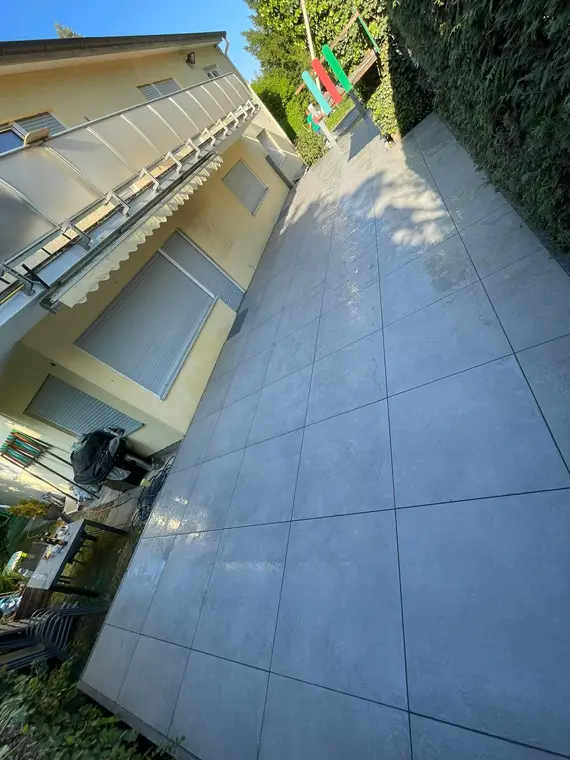 Neu verlegte Graue Terrassenplatten neben einem Wohnhaus