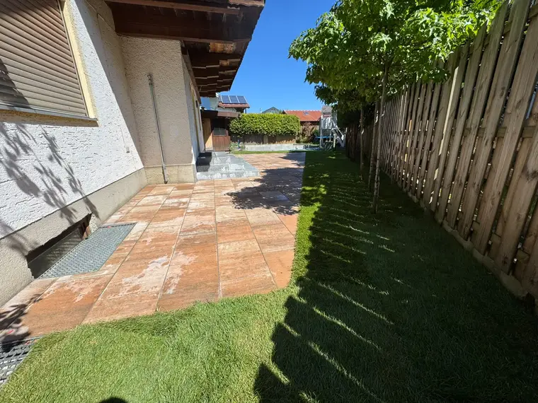 Gepflasterte Terrasse und Gartenstreifen neben einem Wohnhaus