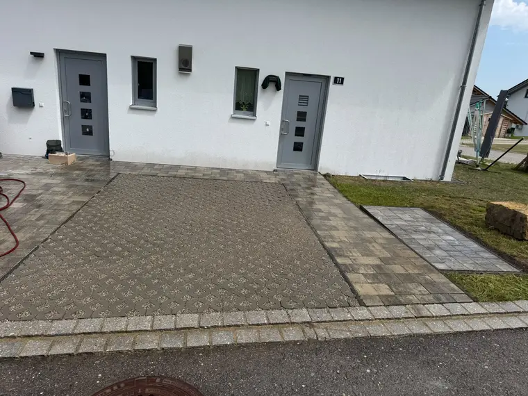 Gepflasterter Einfahrtsbereich vor einem weißen Haus mit Hausnummer 11