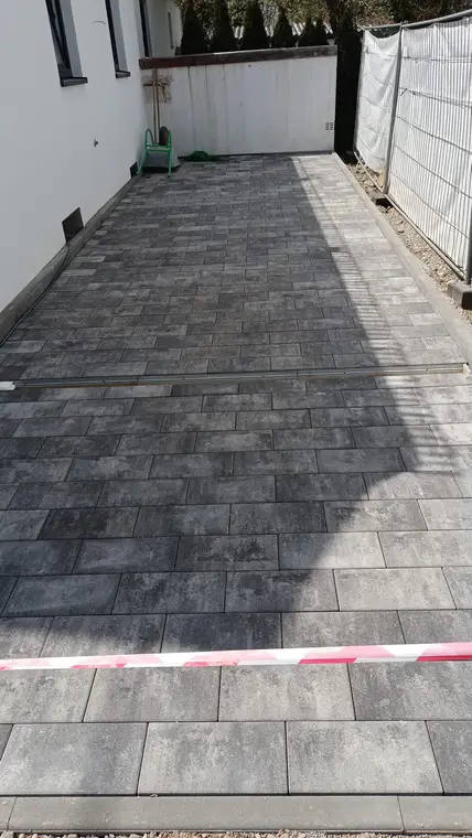 Frisch gepflasterter Hof neben einem Haus mit Absperrband