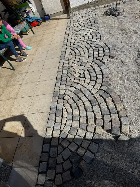 Frisch verlegtes Kopfsteinpflaster in Bogenform im Außenbereich