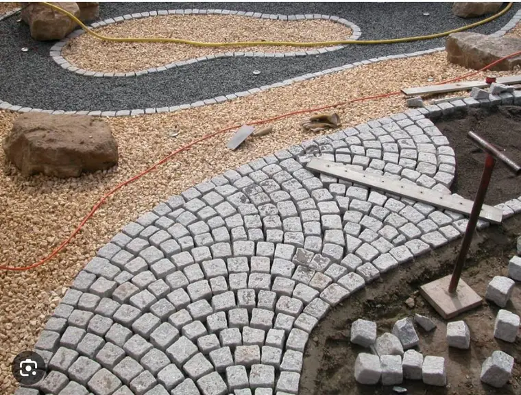 Gepflasterter Gartenweg im Bogen mit Kiesflächen und Werkzeug