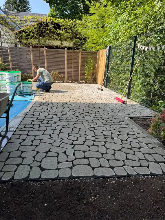 Mann arbeitet an Pflasterarbeiten auf einer Garten-Terrasse