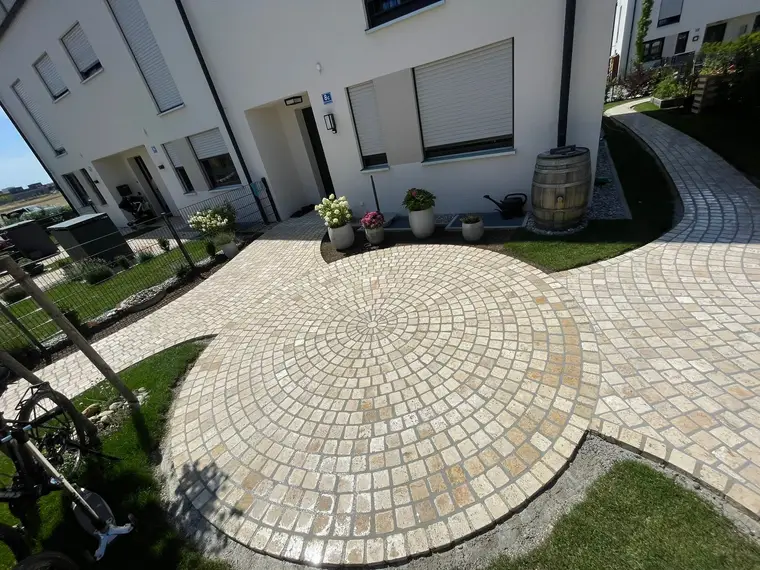 Gepflasterte Kreisfläche und Gehweg vor einem Wohnhaus