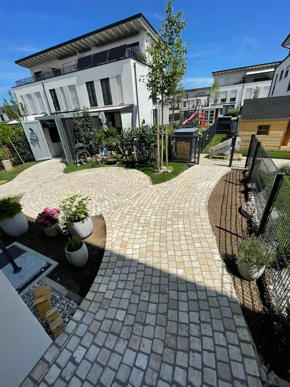 Gepflasterter Gartenweg und Terrasse vor modernen Wohnhäusern
