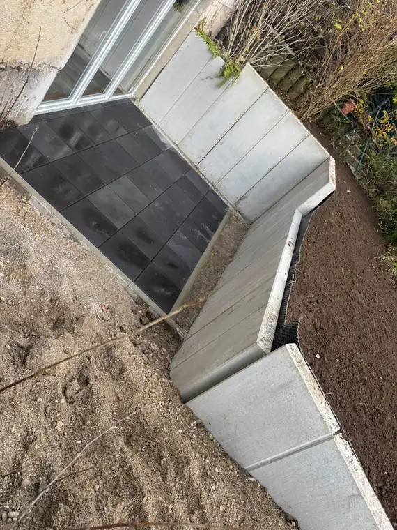 Frisch gepflasterte Terrasse mit Betonstützwänden und Erdreich