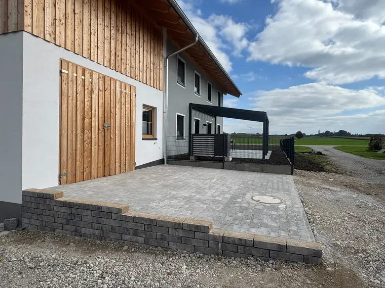 Neubau mit gepflasterter Einfahrt und Holztoren