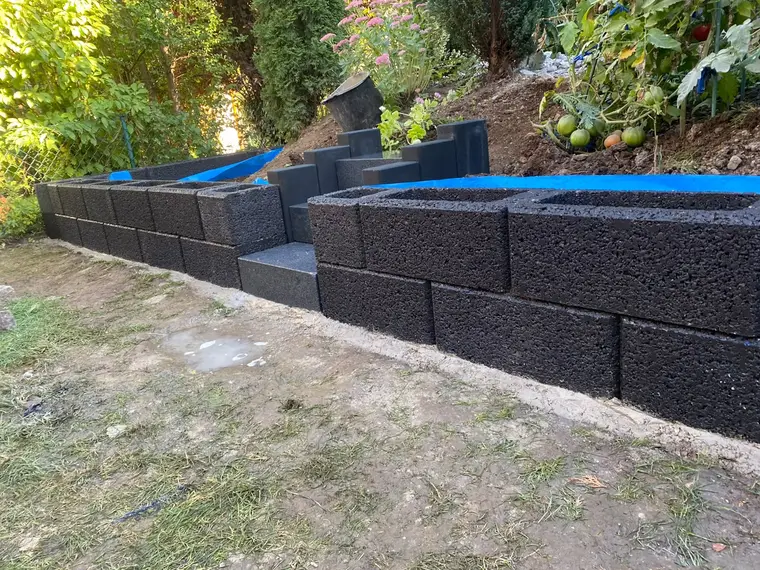 Gartenterrassierung aus schwarzen Pflanzsteinen mit kleiner Treppe