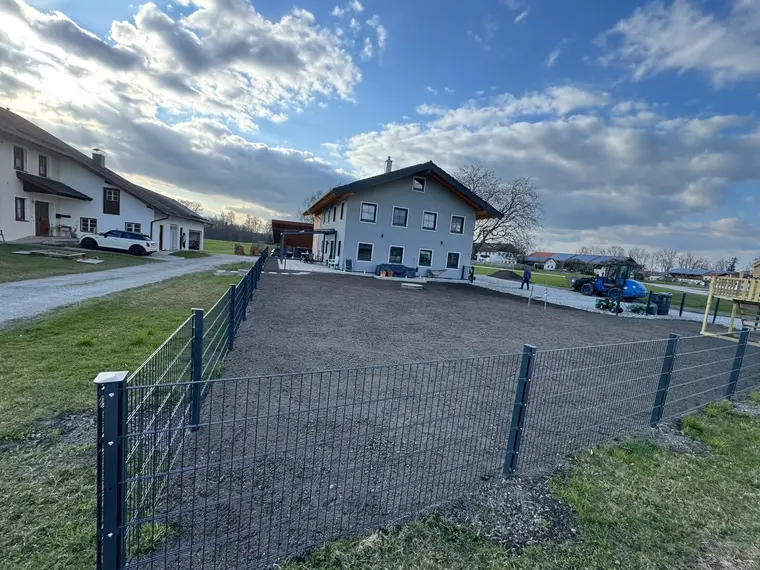 Eingezäunter Gartenbereich vor einem Wohnhaus mit vorbereitetem Boden