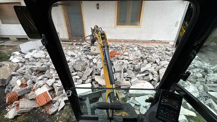 Blick aus Baggerkabine auf Schuttberg vor Haus