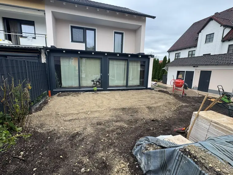 Vorbereiteter Baustellenbereich vor einem Wohnhaus mit Baumaschinen