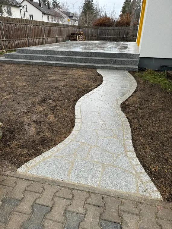 Dieselbe Fläche fertig: Granitterrasse mit Blockstufen und Polygonalweg